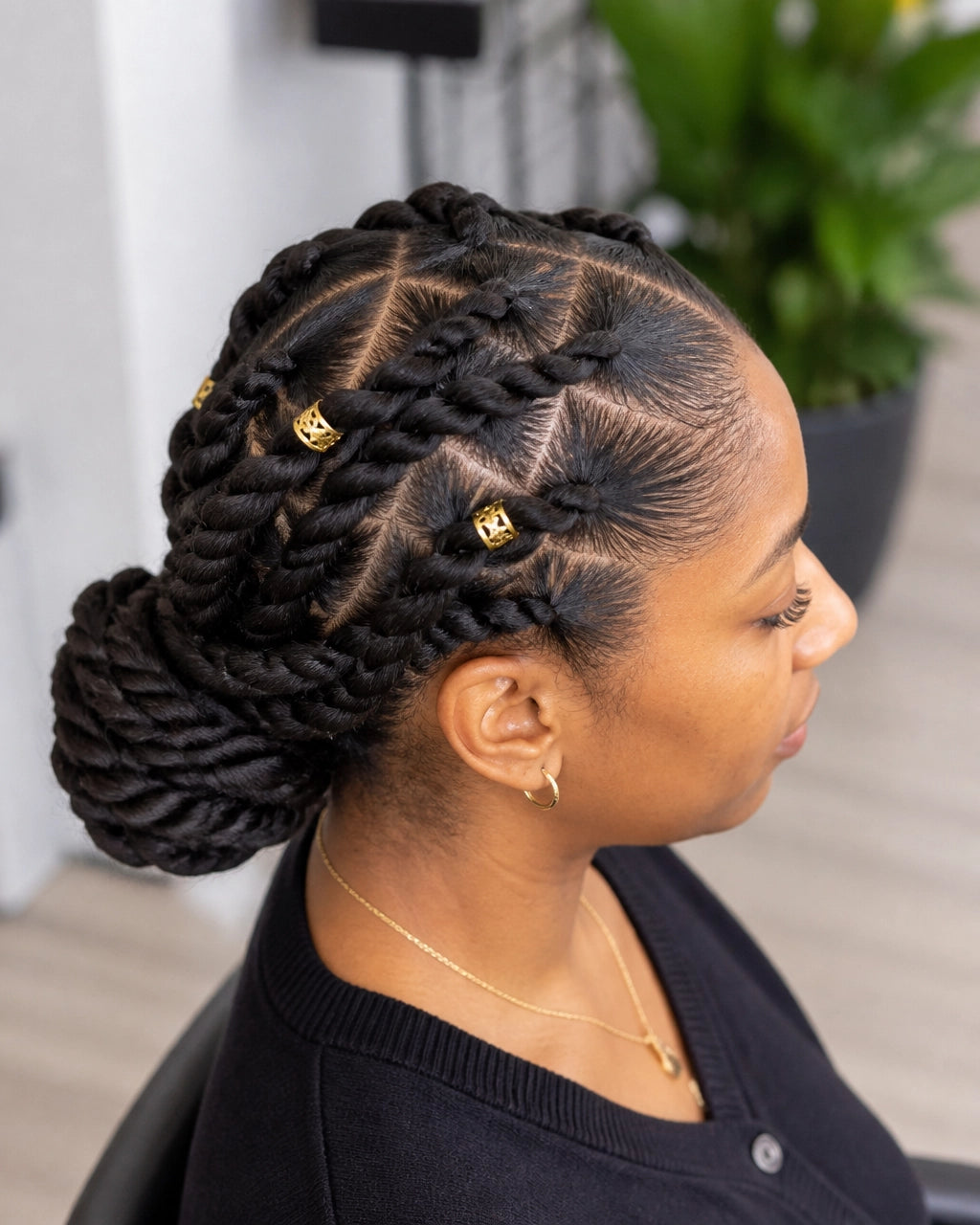 Adult Black woman wearing natural two-strand twists in a low bun with subtle gold cuffs